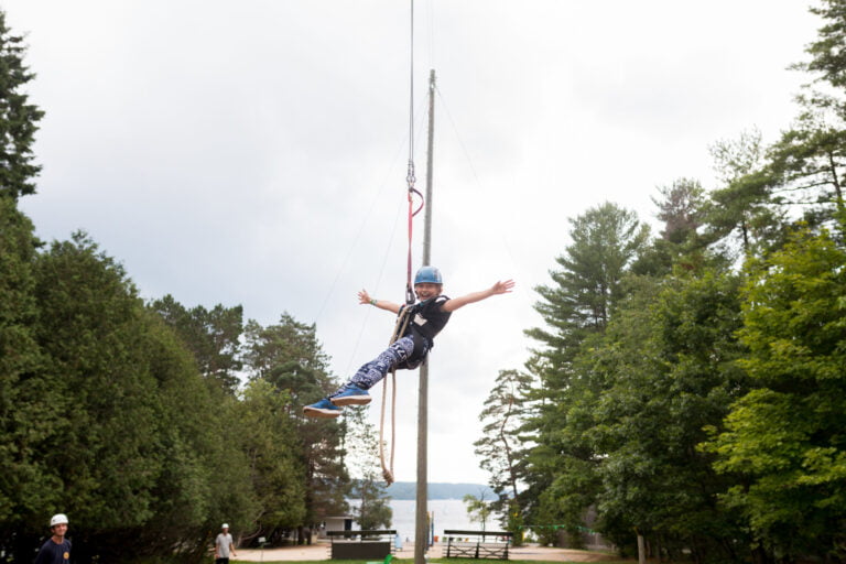 A girl enjoys a zipline ride with her arms reaching out to the sides