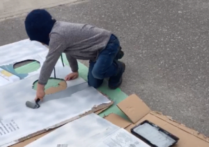 A young boy paints cardboard