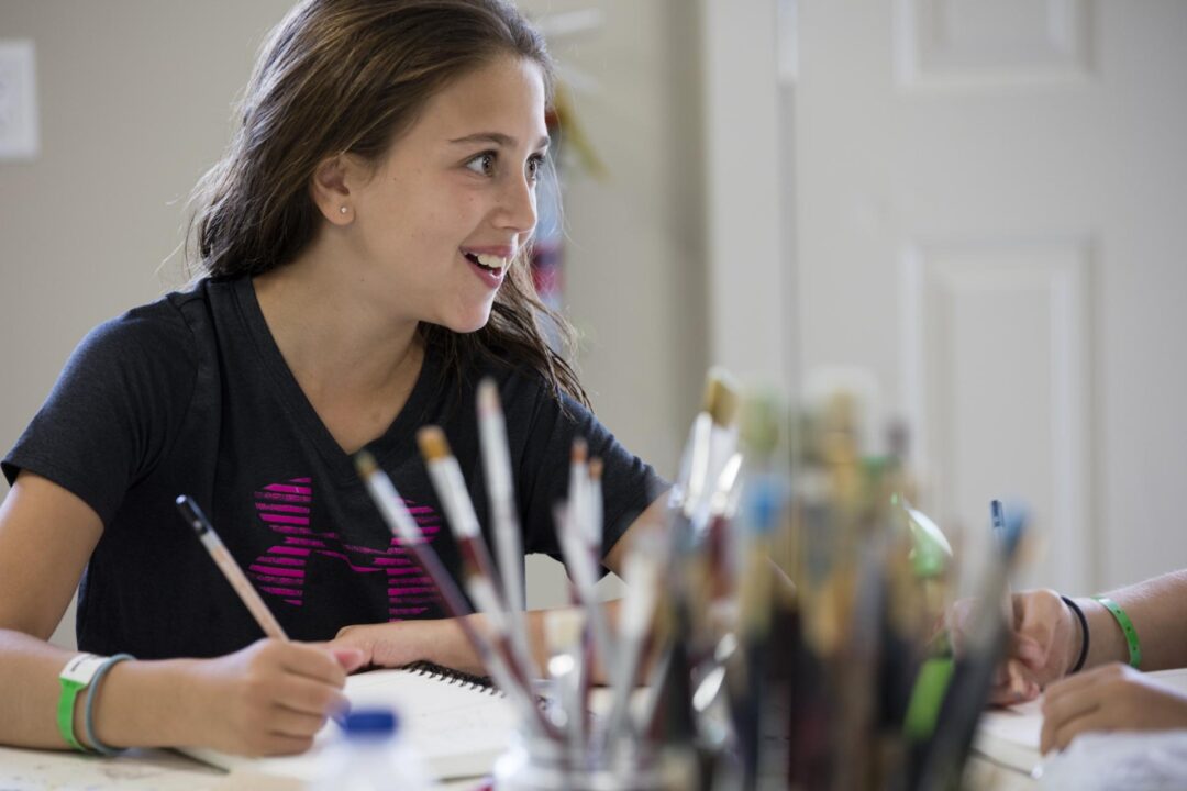 a teen girl smiles while painting