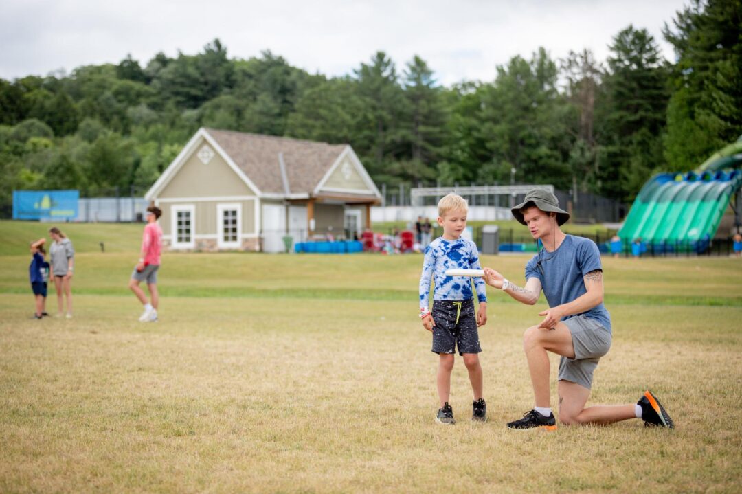 an instructor showing a boy how to throw a frisbee